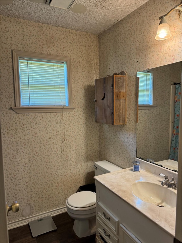 bathroom featuring wood-type flooring, toilet, a textured ceiling, walk in shower, and vanity