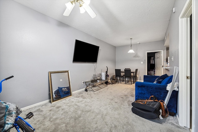 living room with a textured ceiling, carpet flooring, and ceiling fan