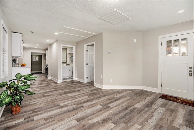 foyer entrance with a textured ceiling and light hardwood / wood-style floors