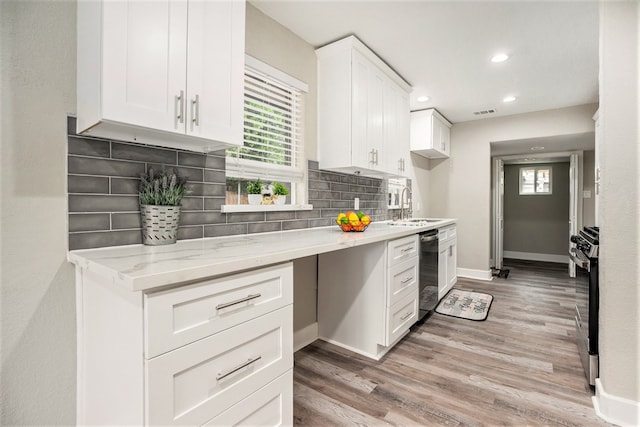 kitchen featuring light wood-type flooring, backsplash, light stone counters, sink, and white cabinets