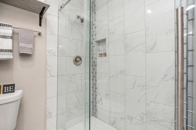 bathroom featuring a shower with shower door and toilet