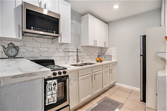 kitchen featuring light tile patterned floors, white cabinetry, stainless steel appliances, and sink