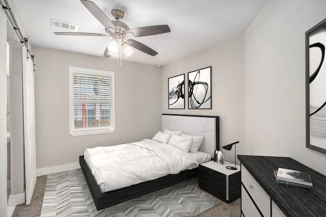 carpeted bedroom featuring a textured ceiling, a barn door, and ceiling fan