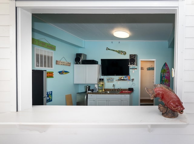 kitchen with sink, stainless steel refrigerator, and white cabinets