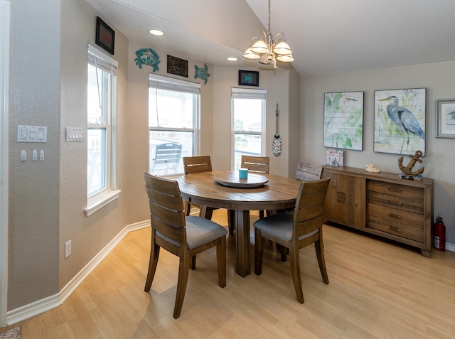 dining area with lofted ceiling, a notable chandelier, and light wood-type flooring