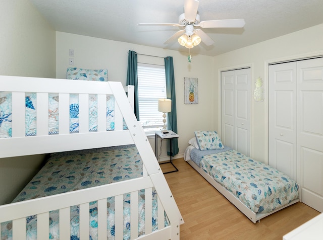 bedroom with light hardwood / wood-style floors, multiple closets, and ceiling fan