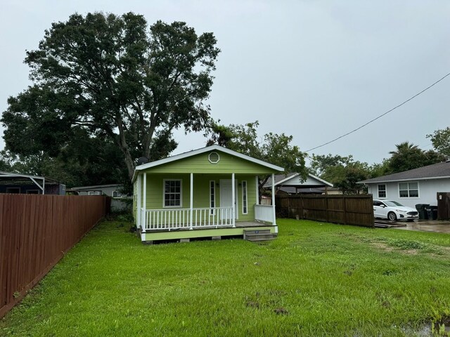 rear view of property featuring a porch and a lawn