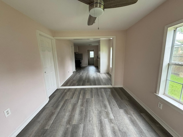 empty room featuring ceiling fan, a wealth of natural light, and dark wood-type flooring