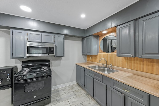 kitchen with gray cabinets, black range with gas cooktop, light tile patterned floors, and sink