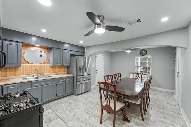 interior space featuring sink, black range oven, light tile patterned floors, stainless steel fridge with ice dispenser, and ceiling fan