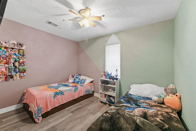 bedroom featuring a textured ceiling, ceiling fan, and light wood-type flooring