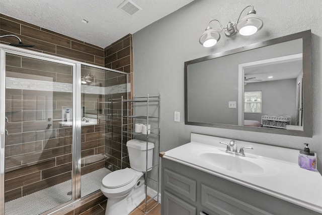 bathroom with vanity, a shower with door, a textured ceiling, and toilet