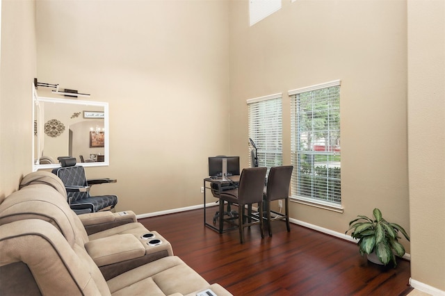 office area featuring a towering ceiling and dark hardwood / wood-style flooring