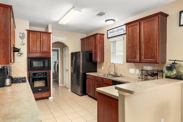 kitchen with backsplash, light tile patterned floors, sink, and black appliances