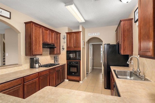 kitchen featuring sink, light tile patterned floors, tasteful backsplash, black appliances, and a textured ceiling