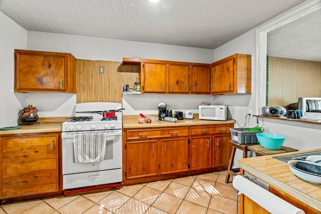 kitchen featuring light tile patterned flooring, a textured ceiling, and white appliances