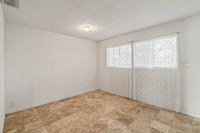 empty room with a textured ceiling and light tile patterned floors