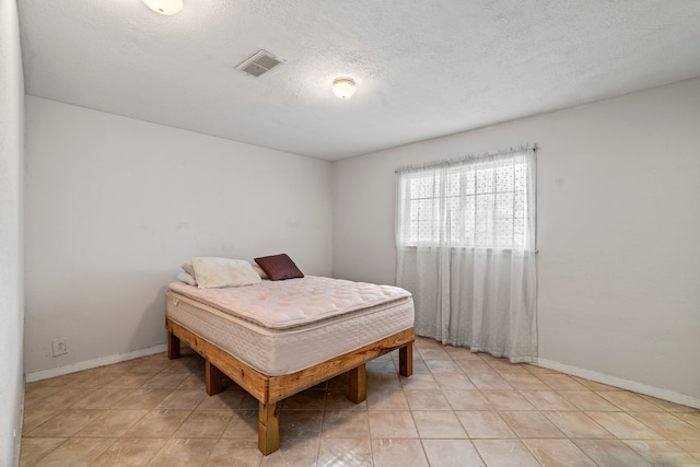 bedroom with light tile patterned floors and a textured ceiling