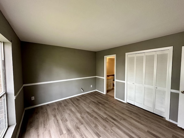 unfurnished bedroom featuring a closet, hardwood / wood-style flooring, and ensuite bathroom