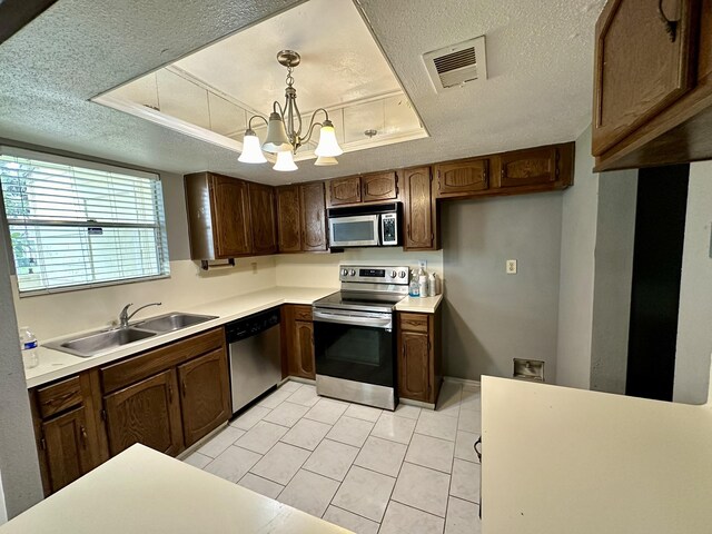 kitchen with sink, appliances with stainless steel finishes, a textured ceiling, and a tray ceiling