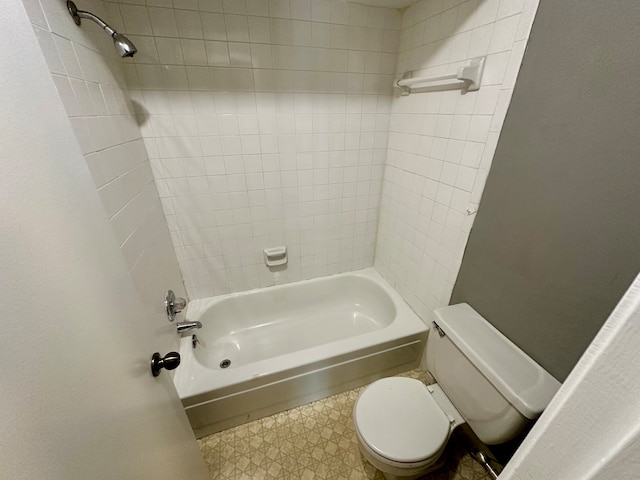 bathroom featuring tiled shower / bath combo, toilet, and tile patterned floors