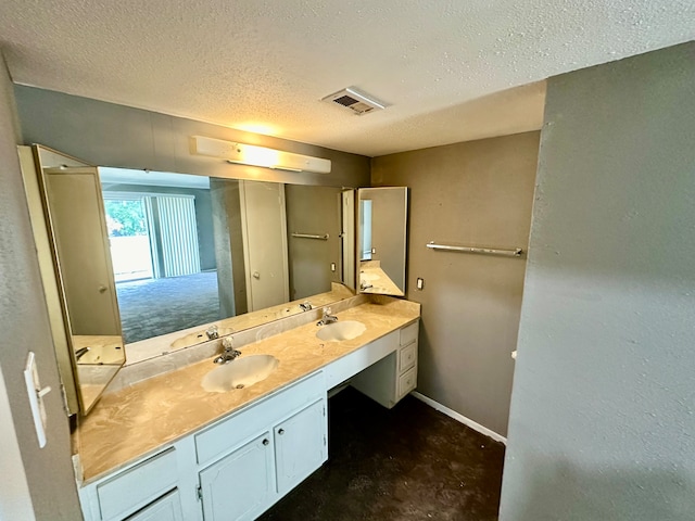 bathroom with dual vanity and a textured ceiling