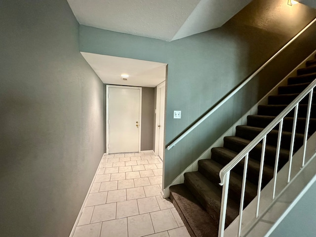 stairway featuring a textured ceiling and light tile patterned floors