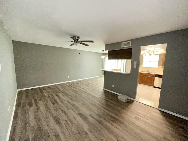 unfurnished living room with ceiling fan, wood-type flooring, and sink