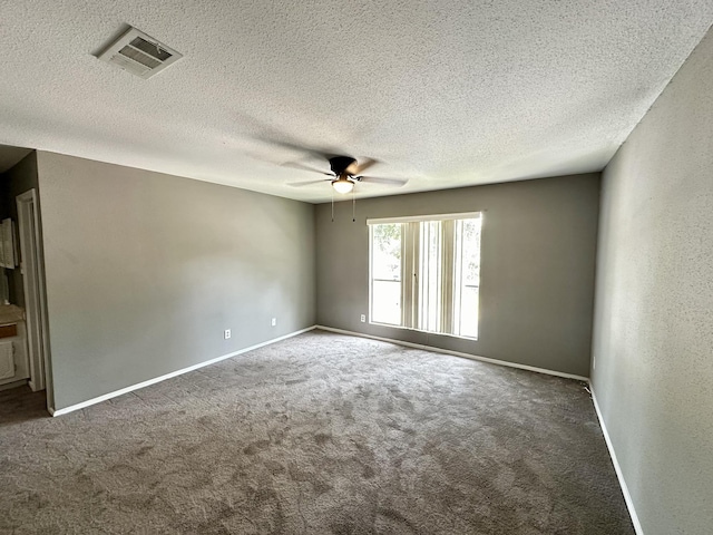 empty room featuring dark carpet, ceiling fan, and a textured ceiling