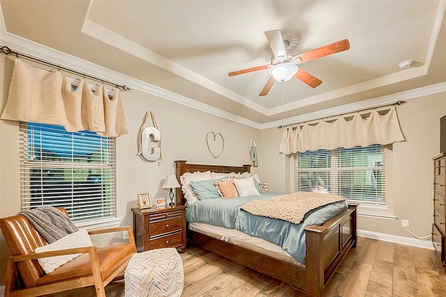 bedroom with ceiling fan, light hardwood / wood-style flooring, and a tray ceiling