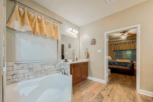 bathroom featuring vanity, ceiling fan, a washtub, and hardwood / wood-style flooring