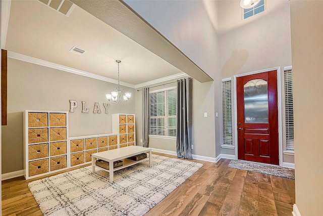 foyer entrance featuring a chandelier, crown molding, and hardwood / wood-style floors