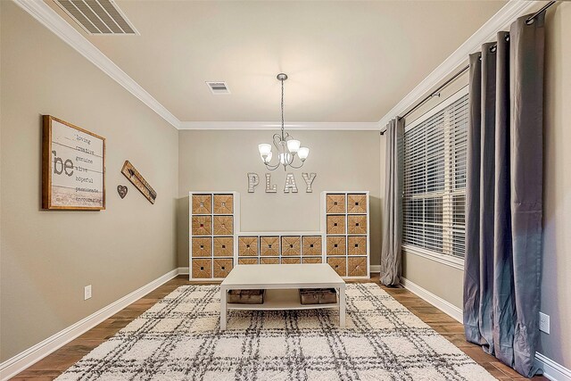 dining space with hardwood / wood-style flooring, crown molding, and a chandelier