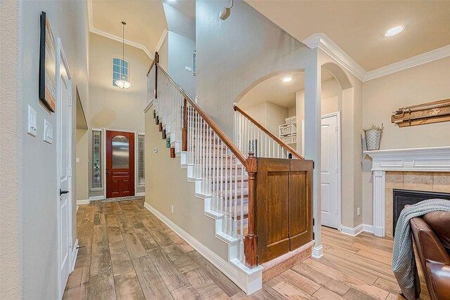 foyer entrance featuring crown molding, a fireplace, and light hardwood / wood-style flooring