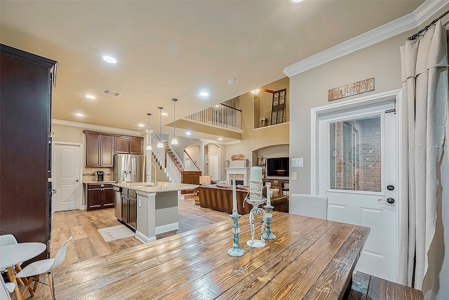 kitchen featuring light hardwood / wood-style flooring, an island with sink, light stone countertops, hanging light fixtures, and sink