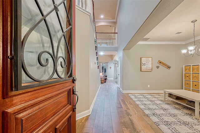 foyer entrance featuring a high ceiling, a chandelier, hardwood / wood-style flooring, and ornamental molding