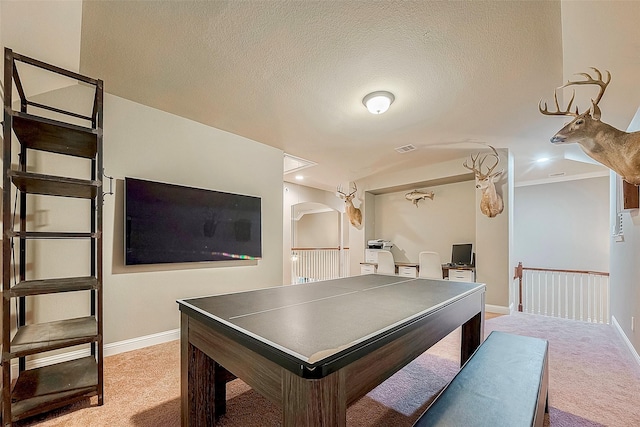 rec room featuring light carpet and a textured ceiling