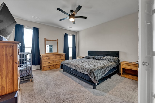 carpeted bedroom featuring multiple windows and ceiling fan