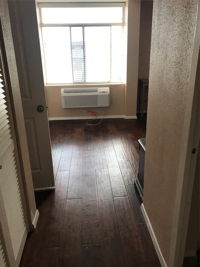 hallway featuring dark hardwood / wood-style floors, an AC wall unit, and a wealth of natural light