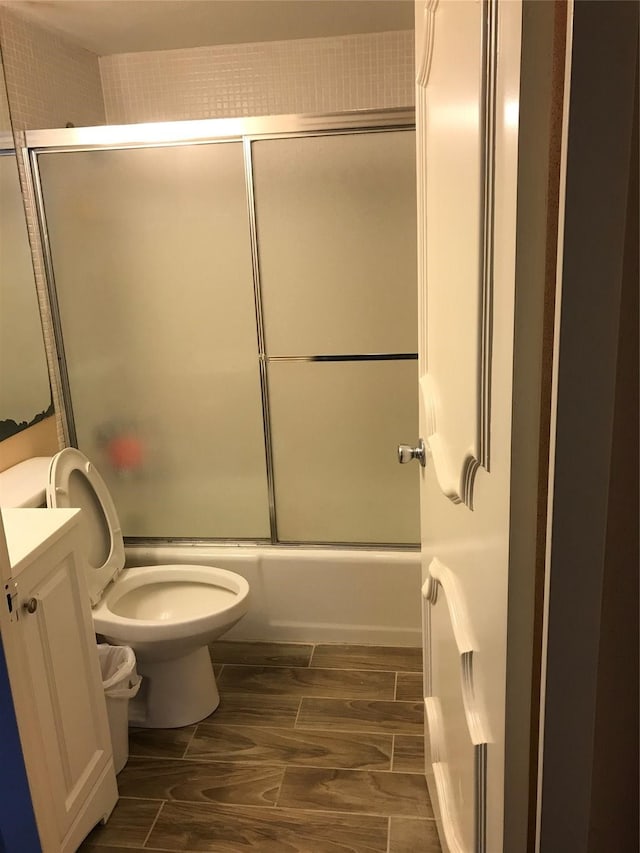 full bathroom featuring bath / shower combo with glass door, toilet, and vanity