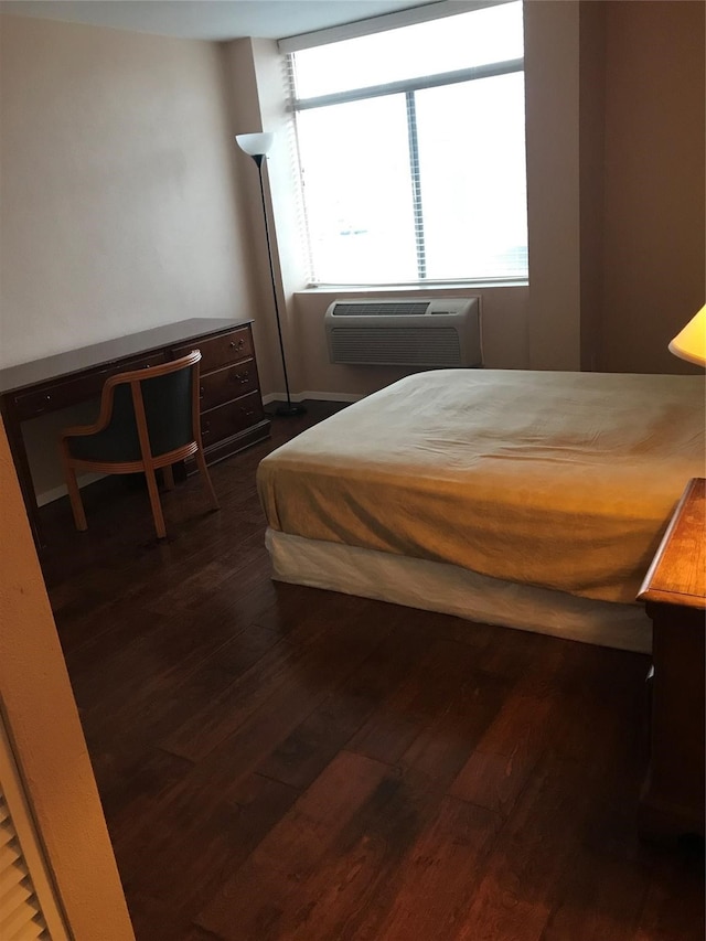 bedroom featuring a wall mounted AC, multiple windows, and dark hardwood / wood-style floors