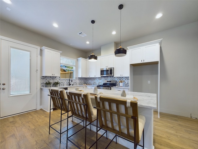 kitchen featuring appliances with stainless steel finishes, light hardwood / wood-style flooring, white cabinetry, and a center island