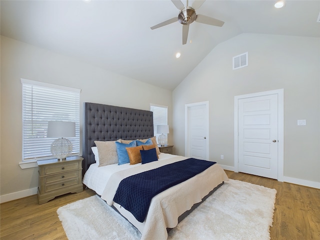 bedroom with light hardwood / wood-style floors, high vaulted ceiling, multiple windows, and ceiling fan