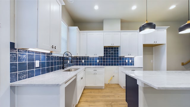 kitchen with hanging light fixtures, light hardwood / wood-style floors, white cabinets, light stone counters, and decorative backsplash