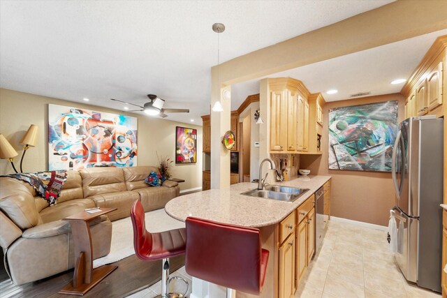 kitchen featuring light tile patterned flooring, ceiling fan, stainless steel appliances, light brown cabinetry, and sink