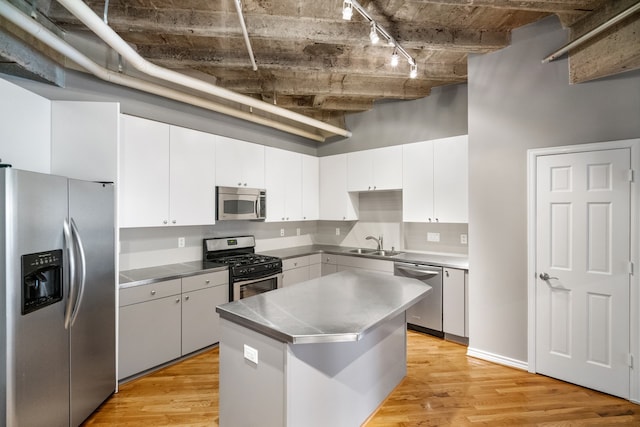 kitchen with stainless steel counters, light hardwood / wood-style flooring, rail lighting, white cabinets, and appliances with stainless steel finishes