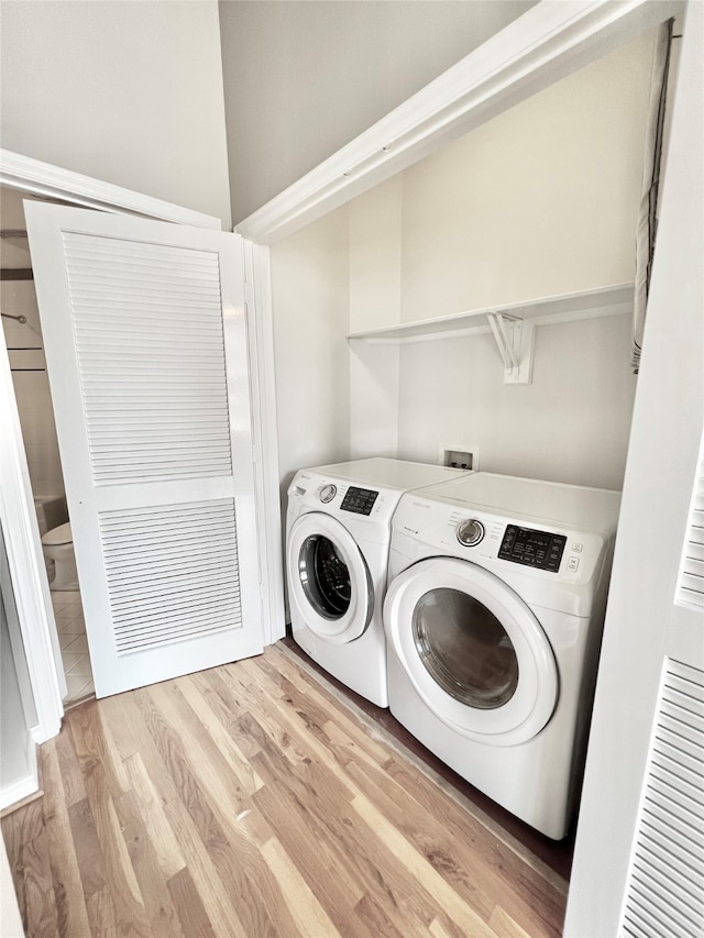 laundry room with washer and clothes dryer and light wood-type flooring