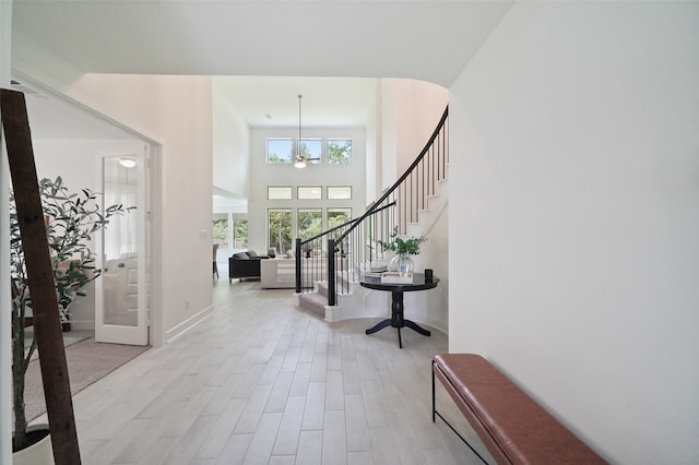 foyer with a high ceiling, a notable chandelier, and light hardwood / wood-style floors