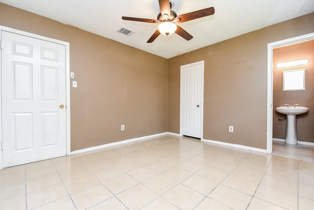 empty room with light tile patterned floors, baseboards, visible vents, and a ceiling fan