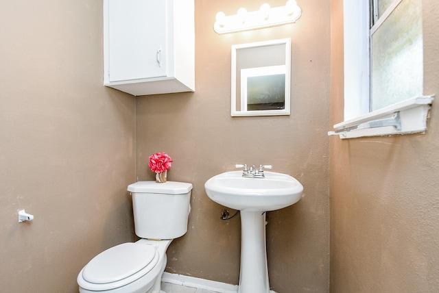 bathroom with toilet, baseboards, and a sink